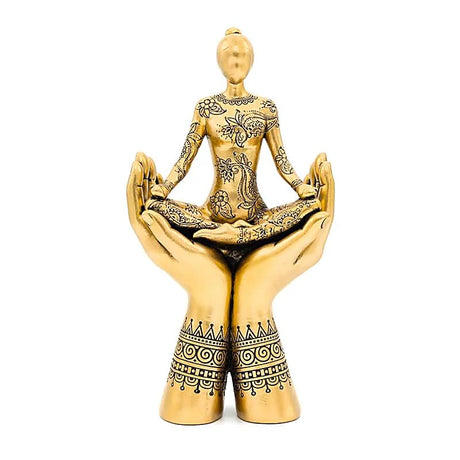 gylden statue af mand siddende i meditations stilling i et par hænder