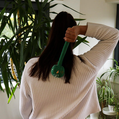 grøn massage hammer som slår på ryggen af en mørkhåret kvinde